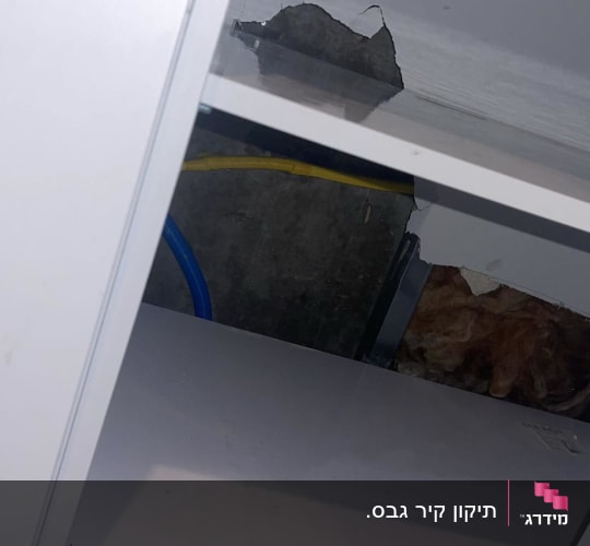ארון פתוח עם חור בקיר וצינורות חשופים